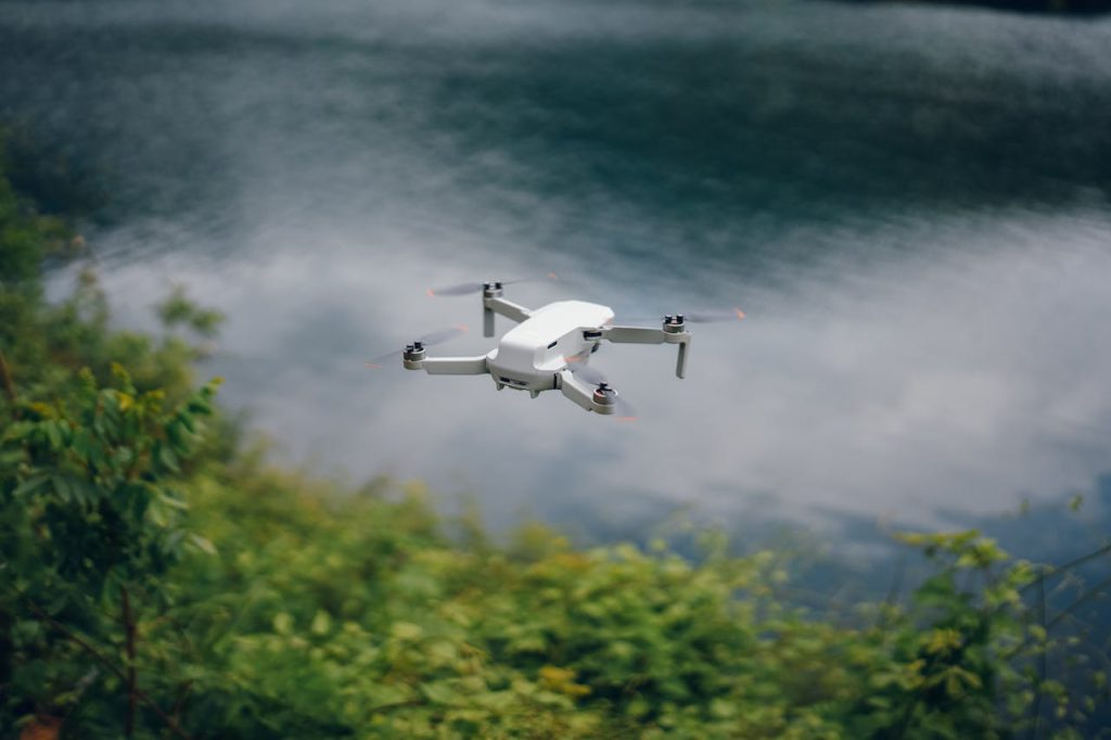 Aerial drone capturing scenic view of lake surrounded by lush greenery.